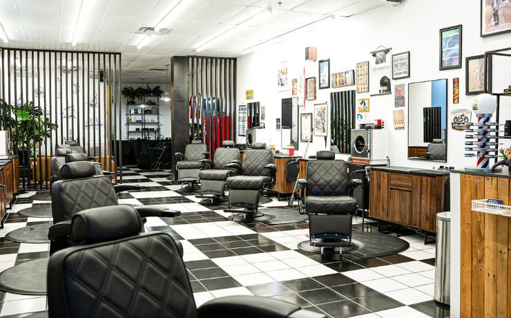 Interior of Olde Soul Barbershop at Southpark Meadows in Austin, TX, featuring sleek black barber chairs, modern decor, and vintage artwork on the walls. The bright, clean space highlights the barbershop’s modern feel with an old soul, offering premium haircuts and grooming services in South Austin.